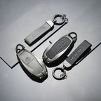 Three professional matte black metal DENZA car key covers with durable rings on a dark surface.