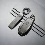 Two professional matte black Denza car key fobs with durable protective casings.
