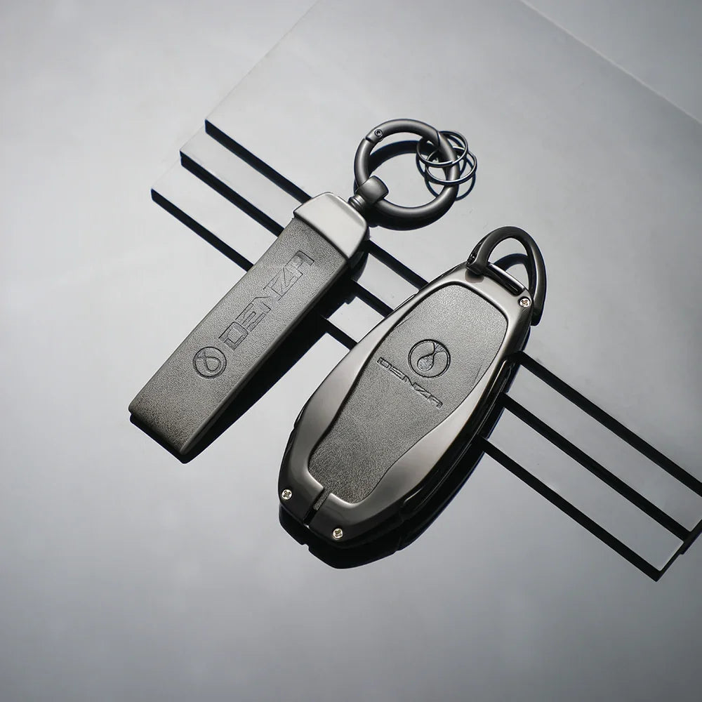 Two professional matte black Denza car key fobs with durable protective casings.