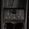 Close-up of a sleek black center console with a rotary gear shifter and touch controls.