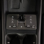Close-up of a sleek black center console with a rotary gear shifter and touch controls.