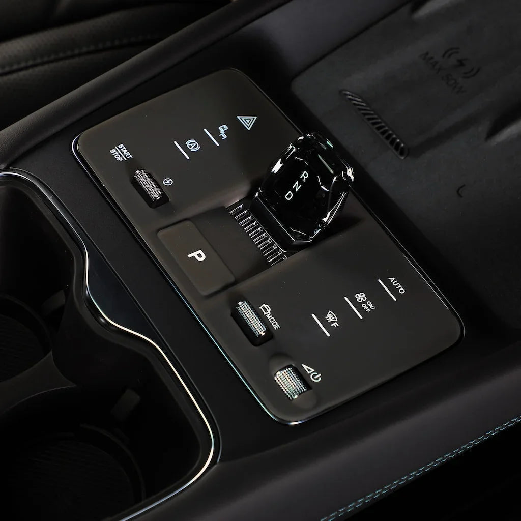 Close-up of a sleek black center console with a crystal-style gear shifter and tactile controls.