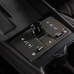 Close-up of a sleek, black glossy gear selector on a brown leather-textured center console.