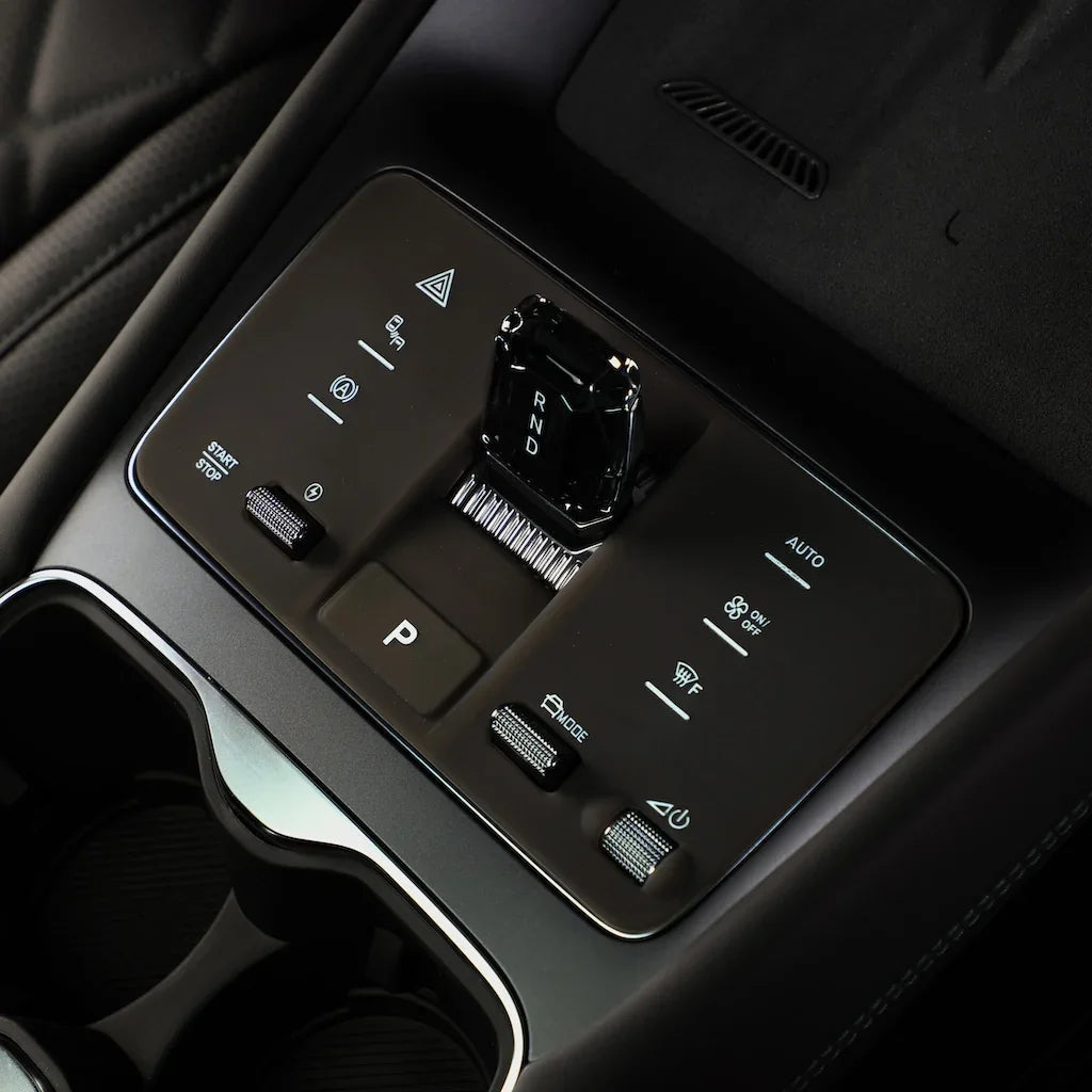 Black premium center console control panel with glossy gear shifter and silver metallic buttons.
