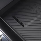 Black heavy-duty rubber car floor mat with textured non-slip surface and drainage slots.