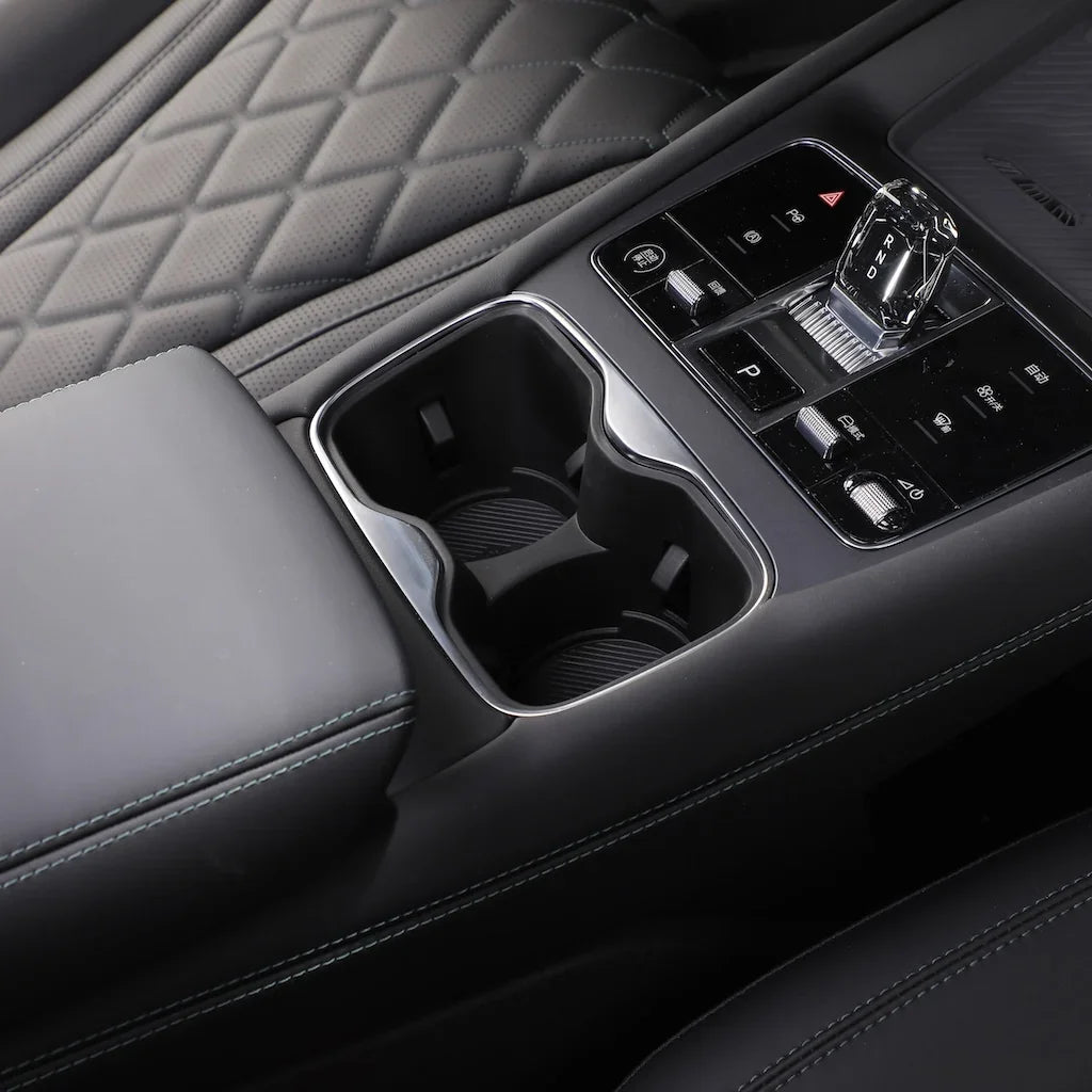 Black leather car interior featuring a dual cup holder and sleek center console controls.