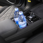 Black leather interior featuring a built-in car cup holder containing two clear plastic water bottles.