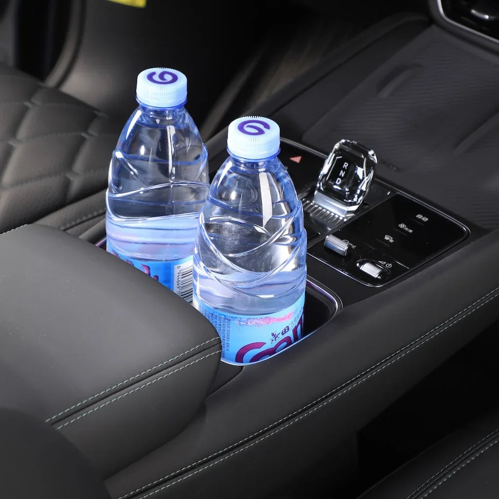 Two clear water bottles in a sleek black car center console cup holder with premium stitching.