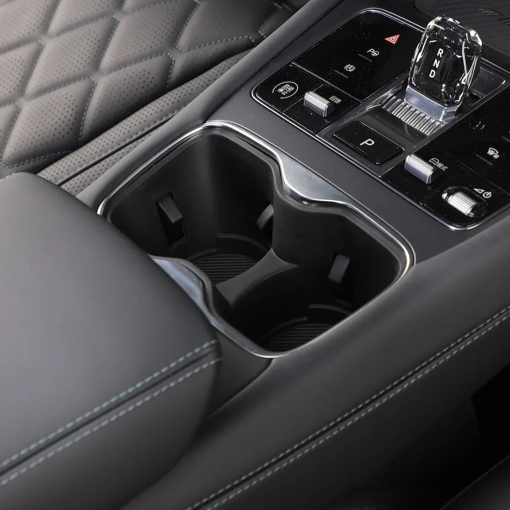 Black leather car interior featuring a dual cup holder and sleek crystal gear shifter.