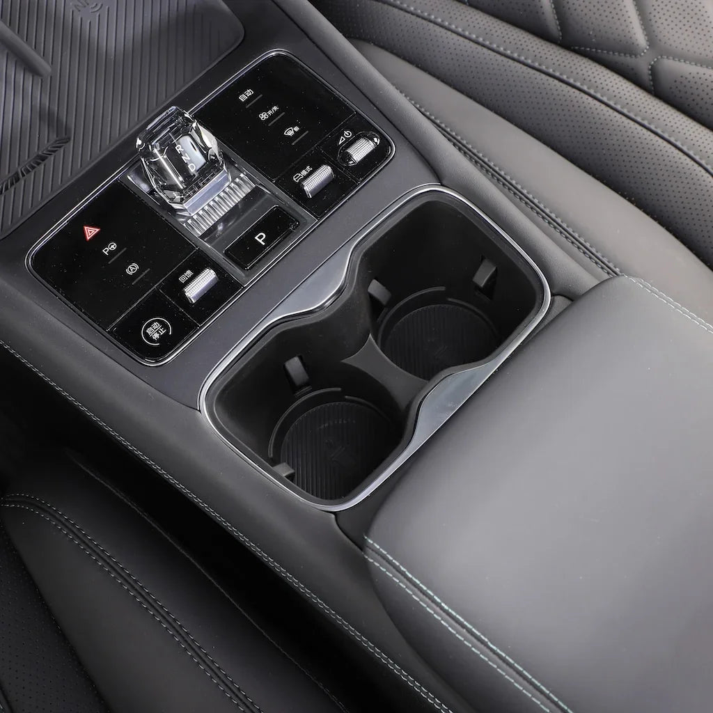 Black leather center console with chrome-trimmed dual cup holders and integrated control buttons.