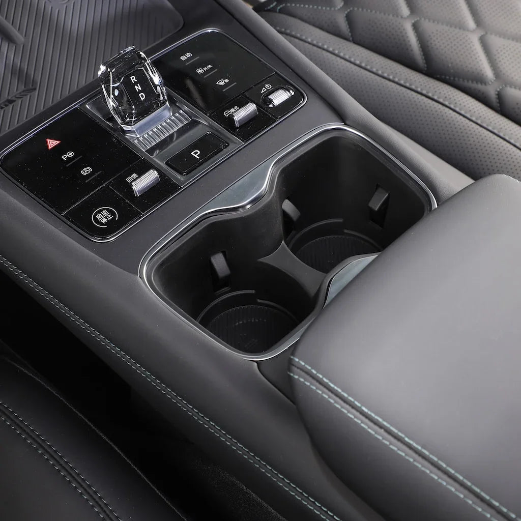 Black leather car center console with crystal gear shifter and dual cup holders.