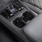 Black leather car center console with crystal gear shifter and dual cup holders.