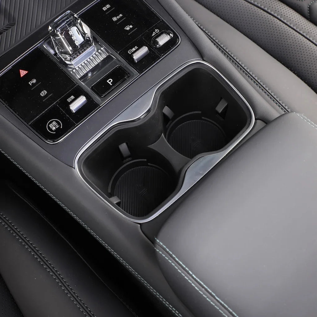 Black leather interior featuring a dual chrome-trimmed cup holder and electronic gear shifter.