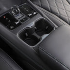 Black leather car center console with dual cup holders and chrome gear shifter.
