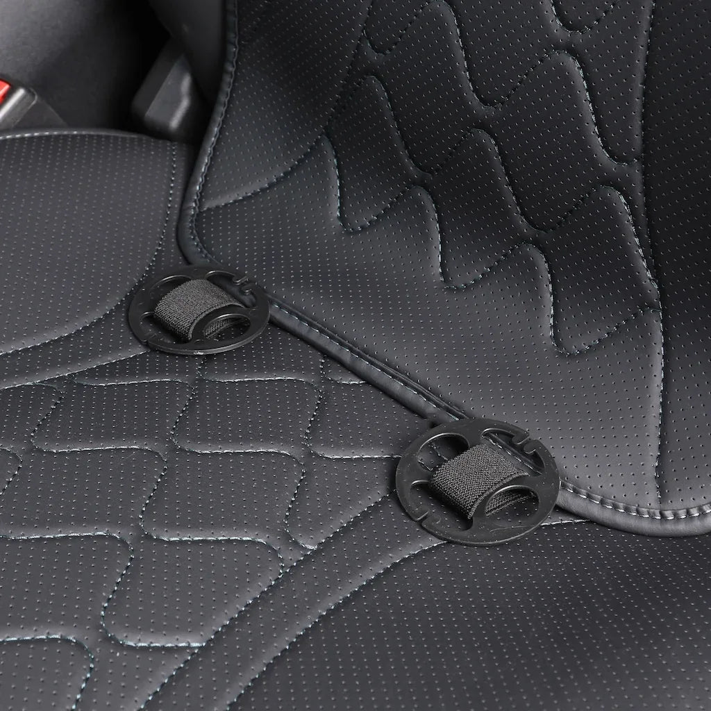 Close-up of black perforated leather car seat covers with quilted stitching and secure fasteners.