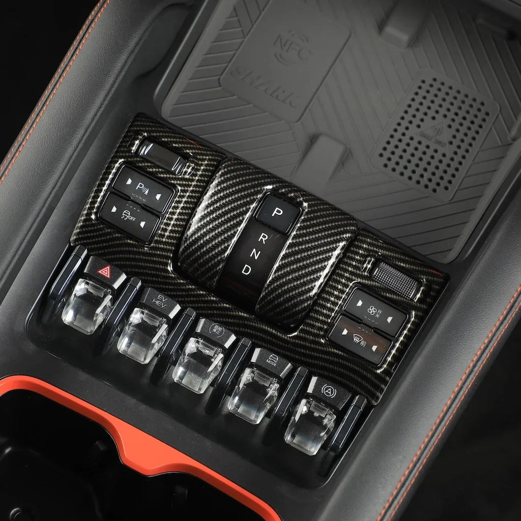 Carbon fiber texture gear shifter panel with P R N D controls and silver metallic accents.