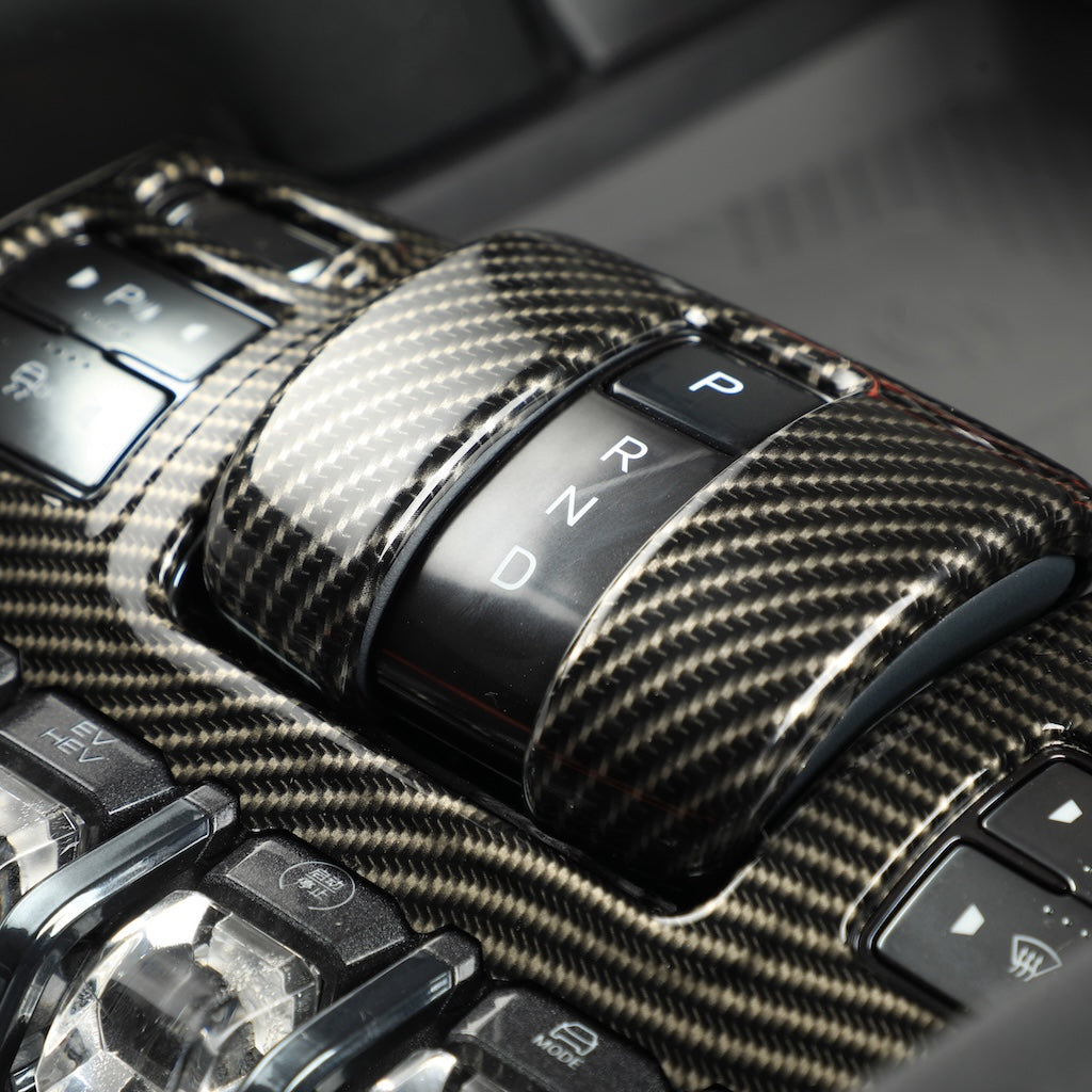 Glossy black carbon fiber gear shifter console with P R N D transmission controls.