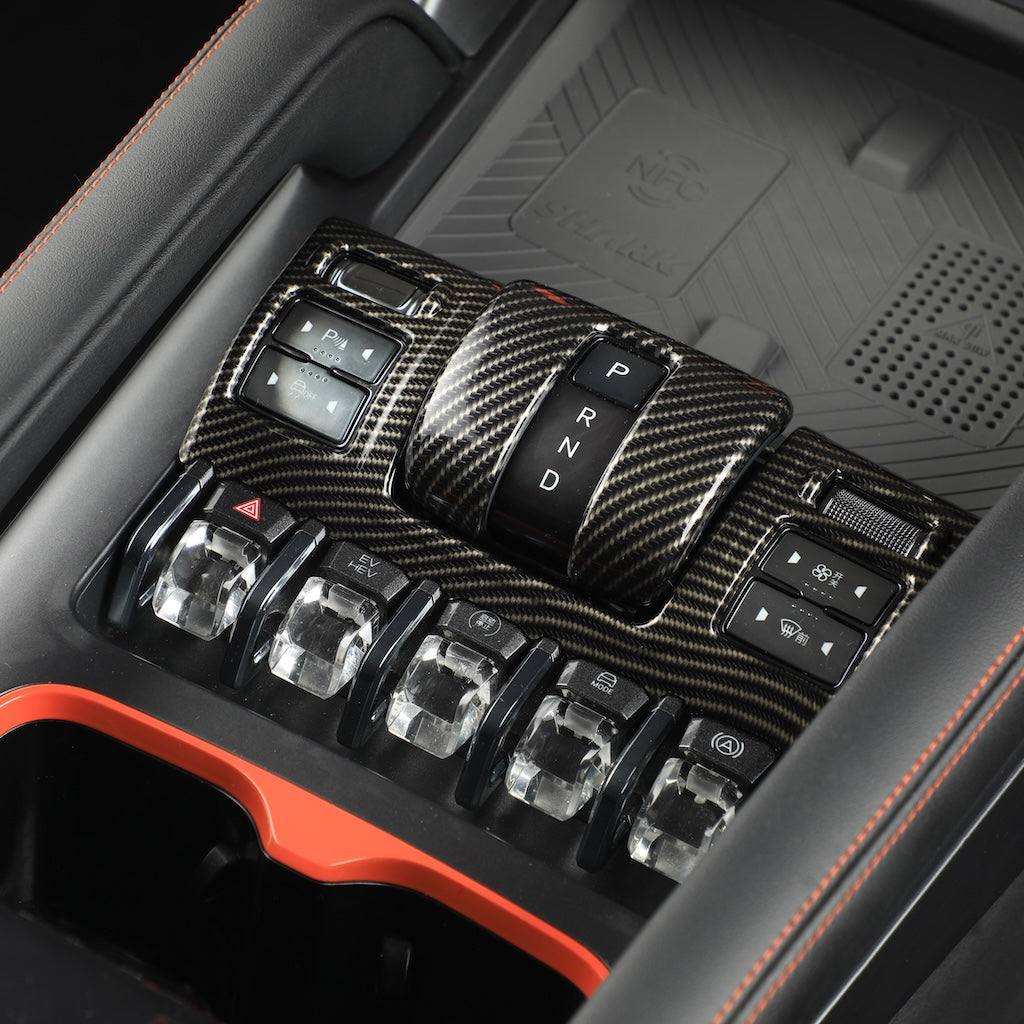 Carbon fiber texture center console trim with black gear shifter and crystal rocker switches.