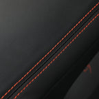 Black premium leather car seat upholstery with contrasting red decorative stitching.