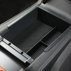 Black textured plastic center console organizer tray with divider for car interior.