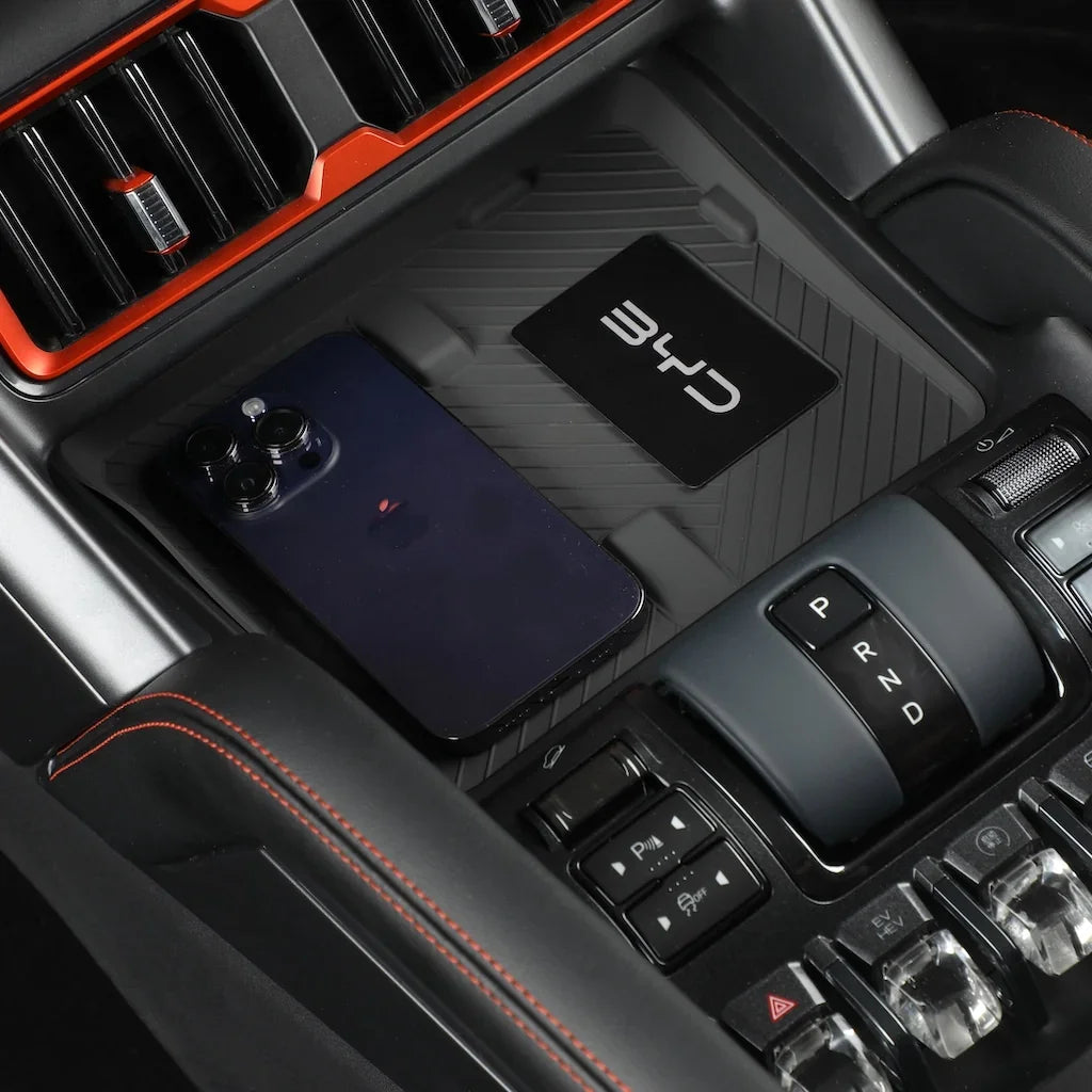 Black matte BYD center console organizer with red stitching and a smartphone.