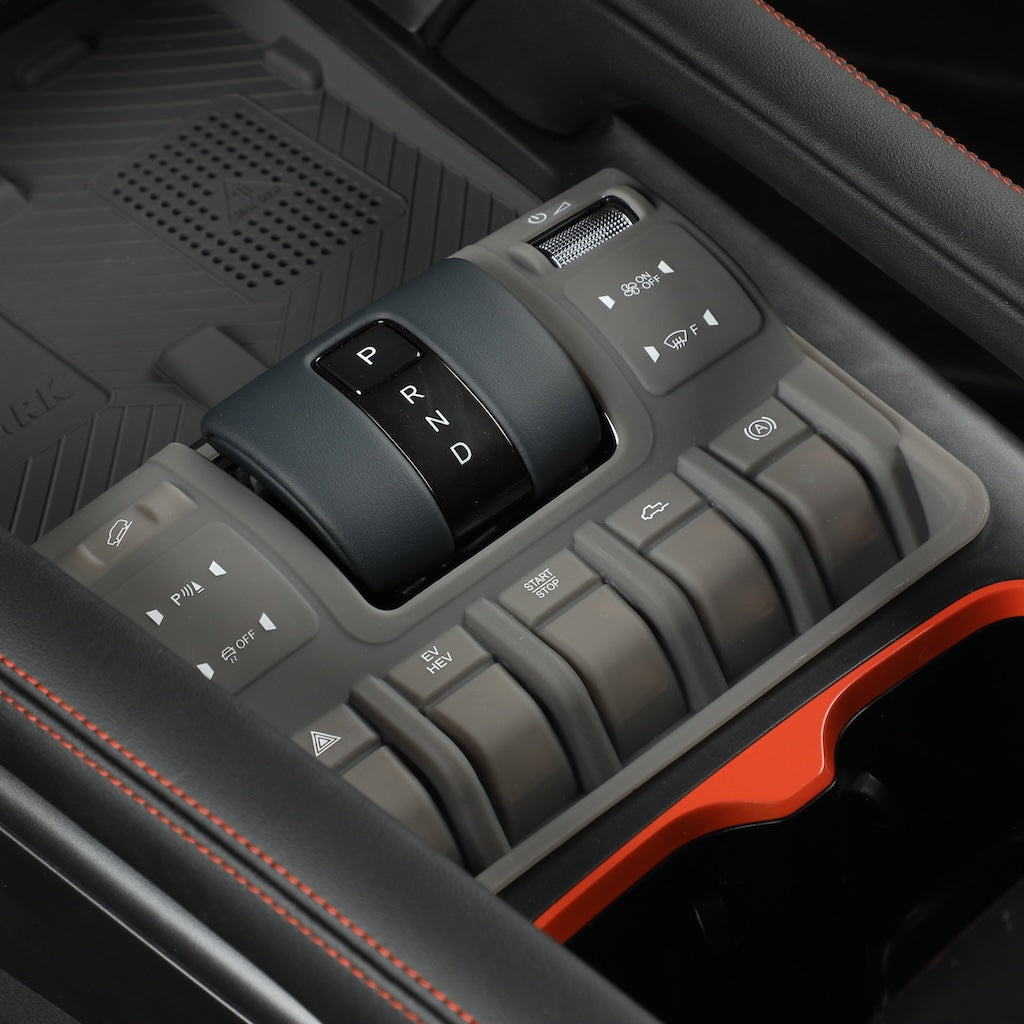 Close-up of a black and grey car center console with gear selector and various buttons.
