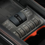 Close-up of a black and grey car center console with gear selector and various buttons.