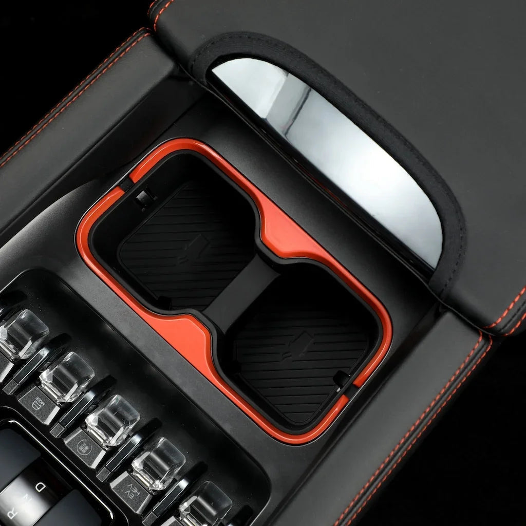Black leather center console organizer with vibrant orange trim and dual storage compartments.