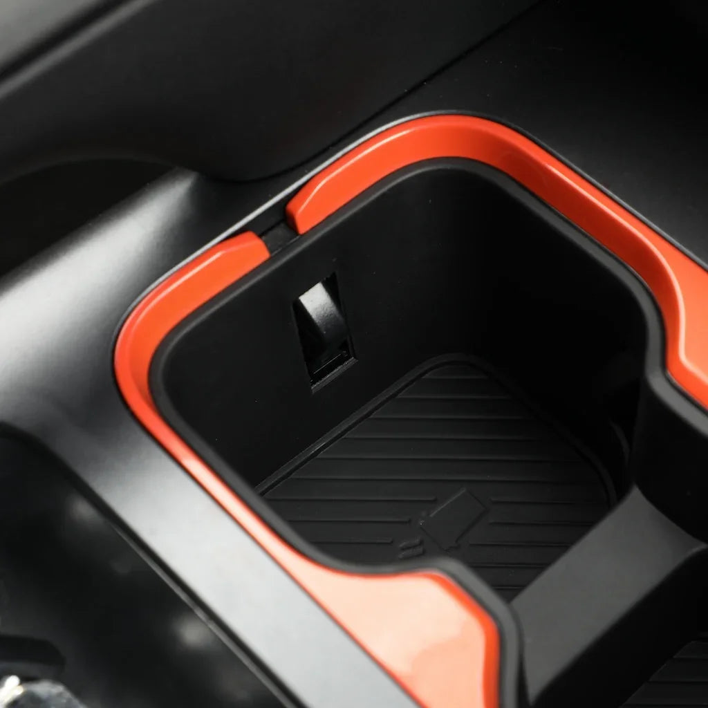 Black car center console cup holder with vibrant orange trim and protective rubber mat.