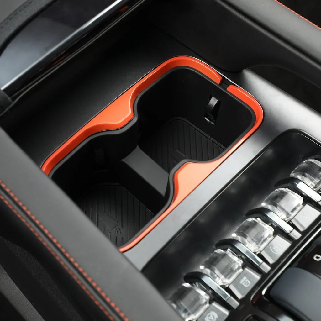 Black car center console cup holder with vibrant orange trim and durable non-slip mat.