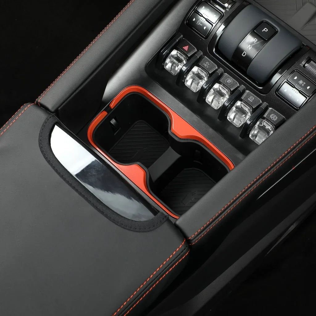 Black leather center console with orange stitching and a red-trimmed dual cup holder organizer.