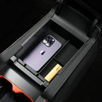 Black matte plastic center console organizer holding a purple smartphone and gold accessory.