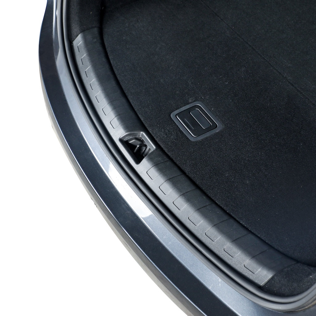 Close-up of a durable black plastic trunk sill protector installed on a grey vehicle.