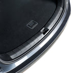 Close-up of a black textured car trunk liner with a protective ribbed edge.
