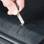 Close-up of a silver key unlocking a durable black textured car accessory.