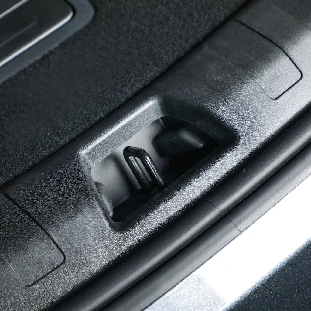 Close-up of a black durable plastic car interior component featuring a metal release lever.