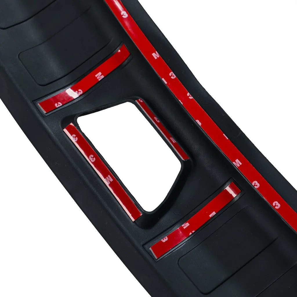 Close-up of black rubber car mat featuring red adhesive strips for secure installation.