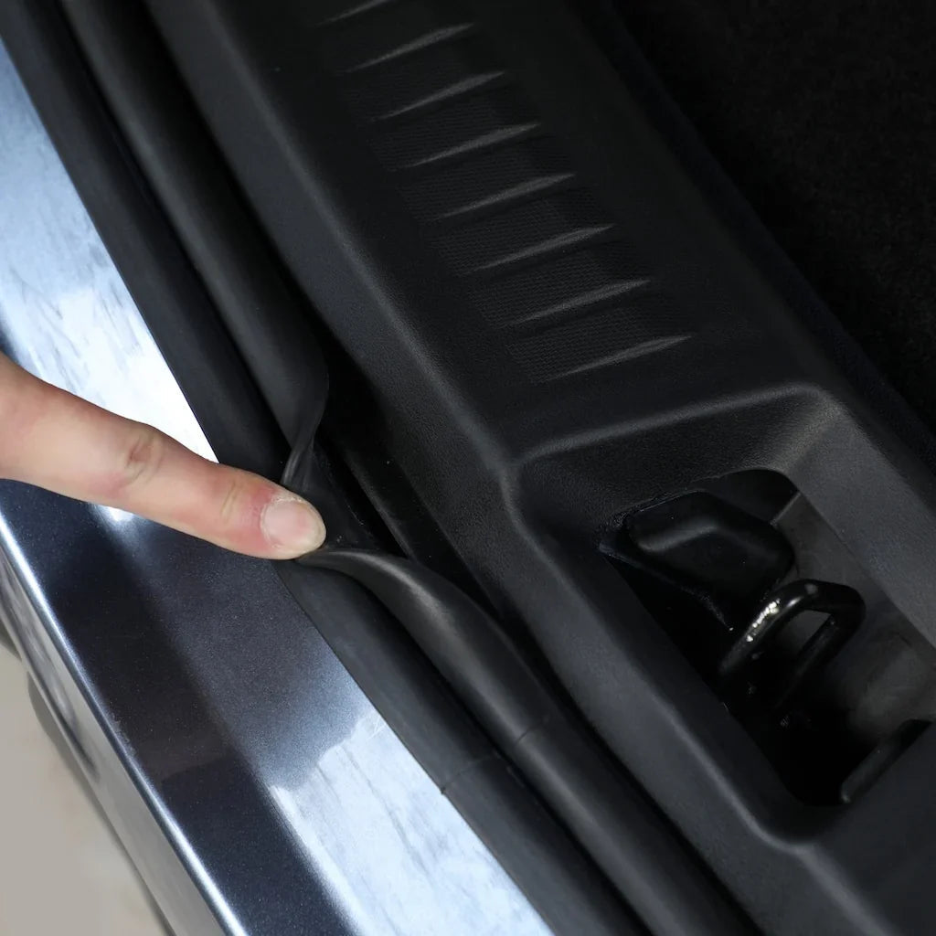 Black flexible rubber weatherstripping seal being installed on a silver car door frame.