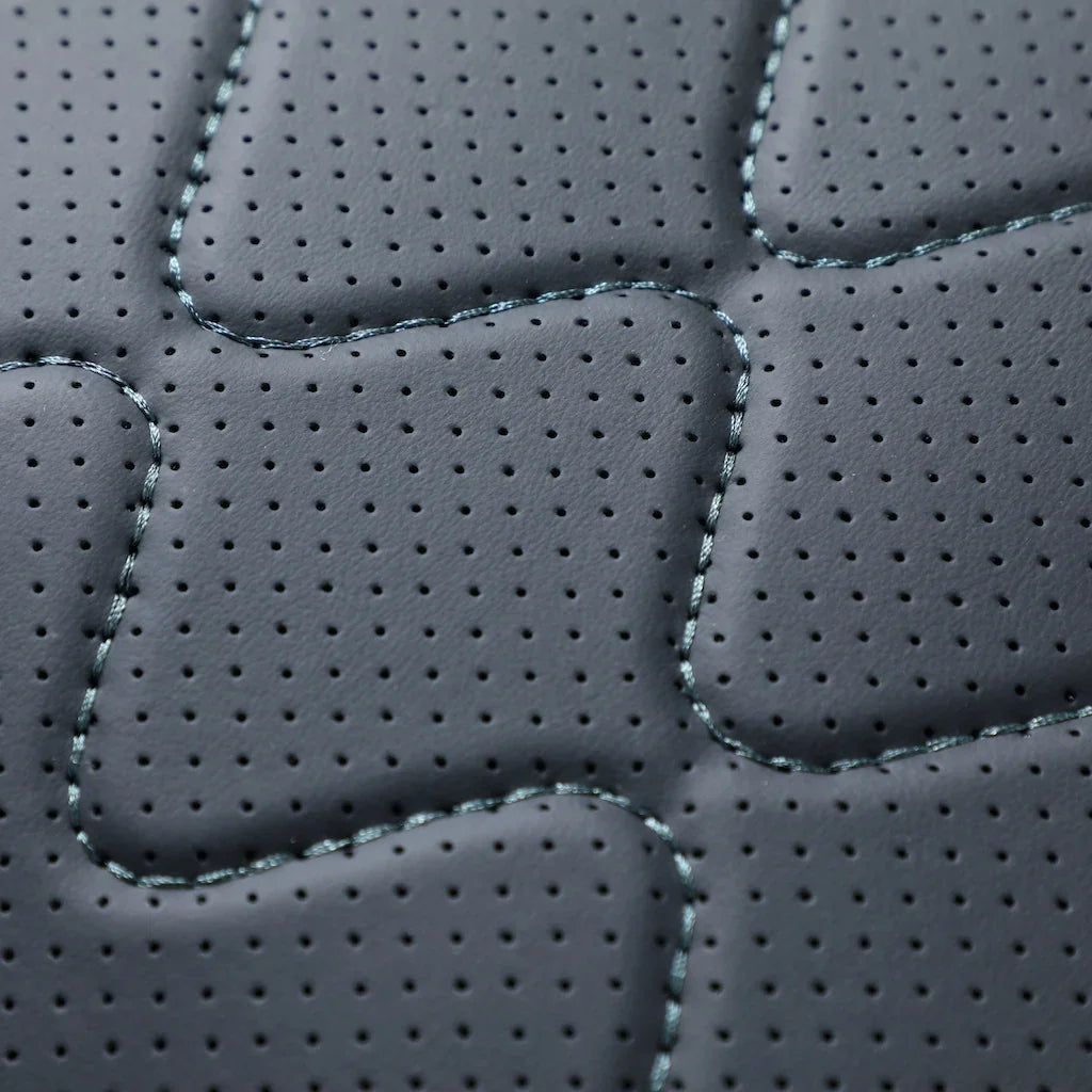 Premium black perforated leather texture with decorative diamond stitching for car interiors.
