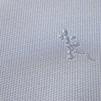 Close-up of a grey textured fabric featuring an embossed lizard logo pattern.