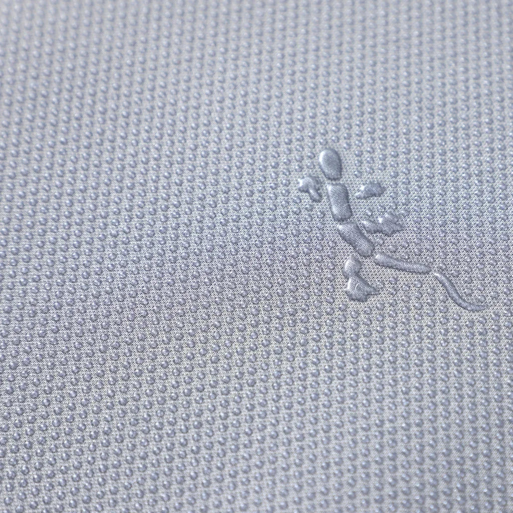 Close-up of a grey textured fabric featuring an embossed lizard logo pattern.
