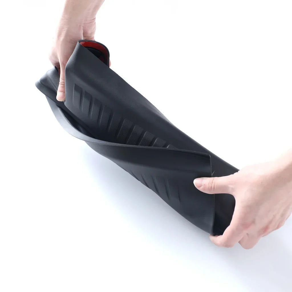 Flexible black TPE car floor mat being bent to demonstrate durability and waterproof material.