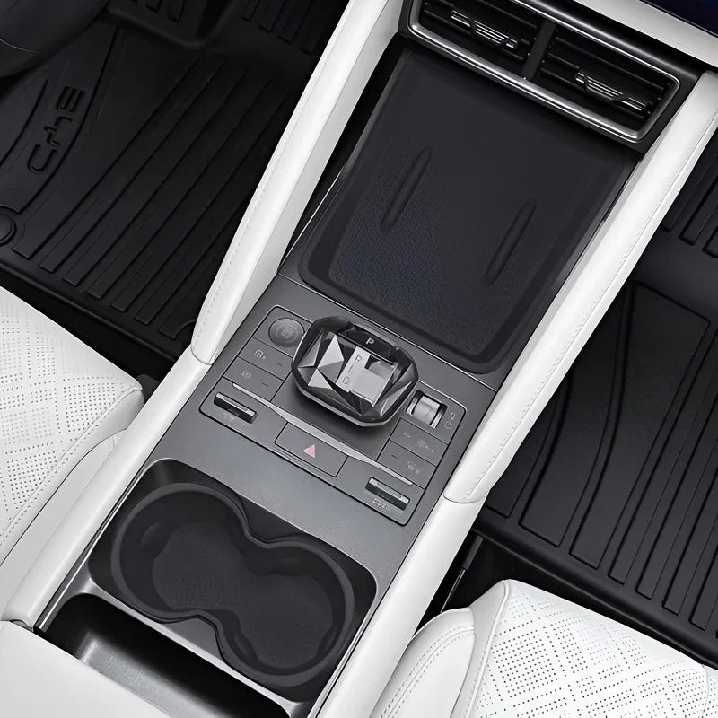 Black textured center console organizer and control panel in a white leather car interior.