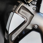 Close-up of a black metallic alloy wheel rim featuring 18X7J size specifications and registration engraving.