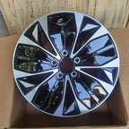 Black and silver dual-tone patterned car wheel hubcap with a glossy finish.
