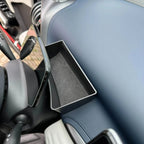Black slim storage organizer tray placed on a blue leather car dashboard interior.