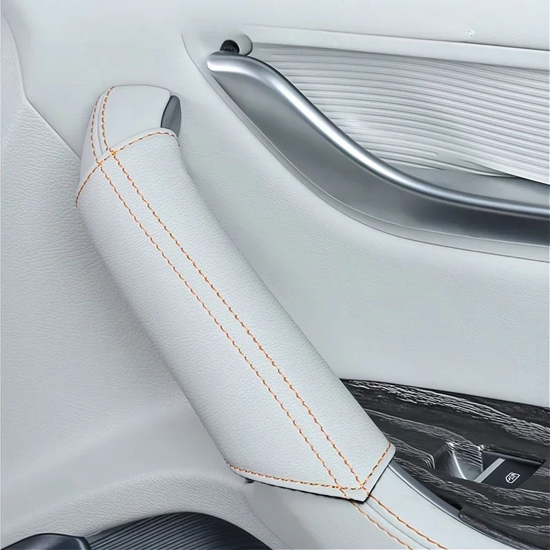 White leather car armrest cover with contrasting orange stitching for interior protection.