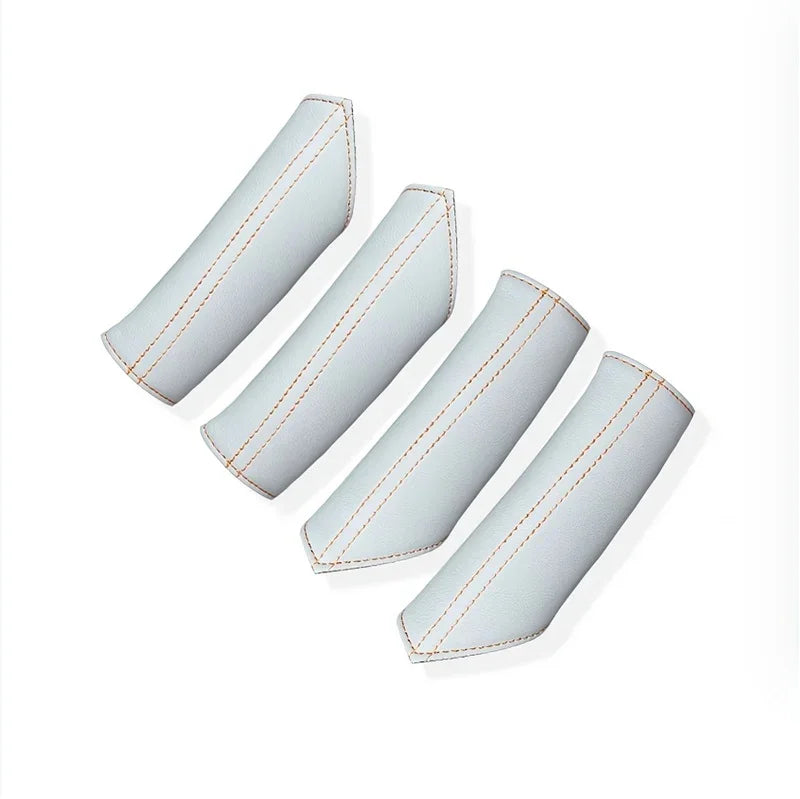 Four white leather car interior accessories with contrasting orange stitching.