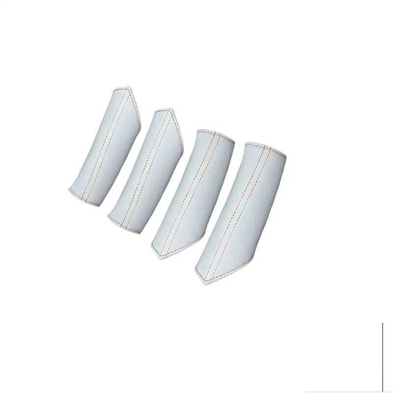 Four white faux leather car interior trim covers with contrasting orange stitching.