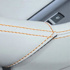 Close-up of premium white leather car seat upholstery with distinctive orange contrast stitching.